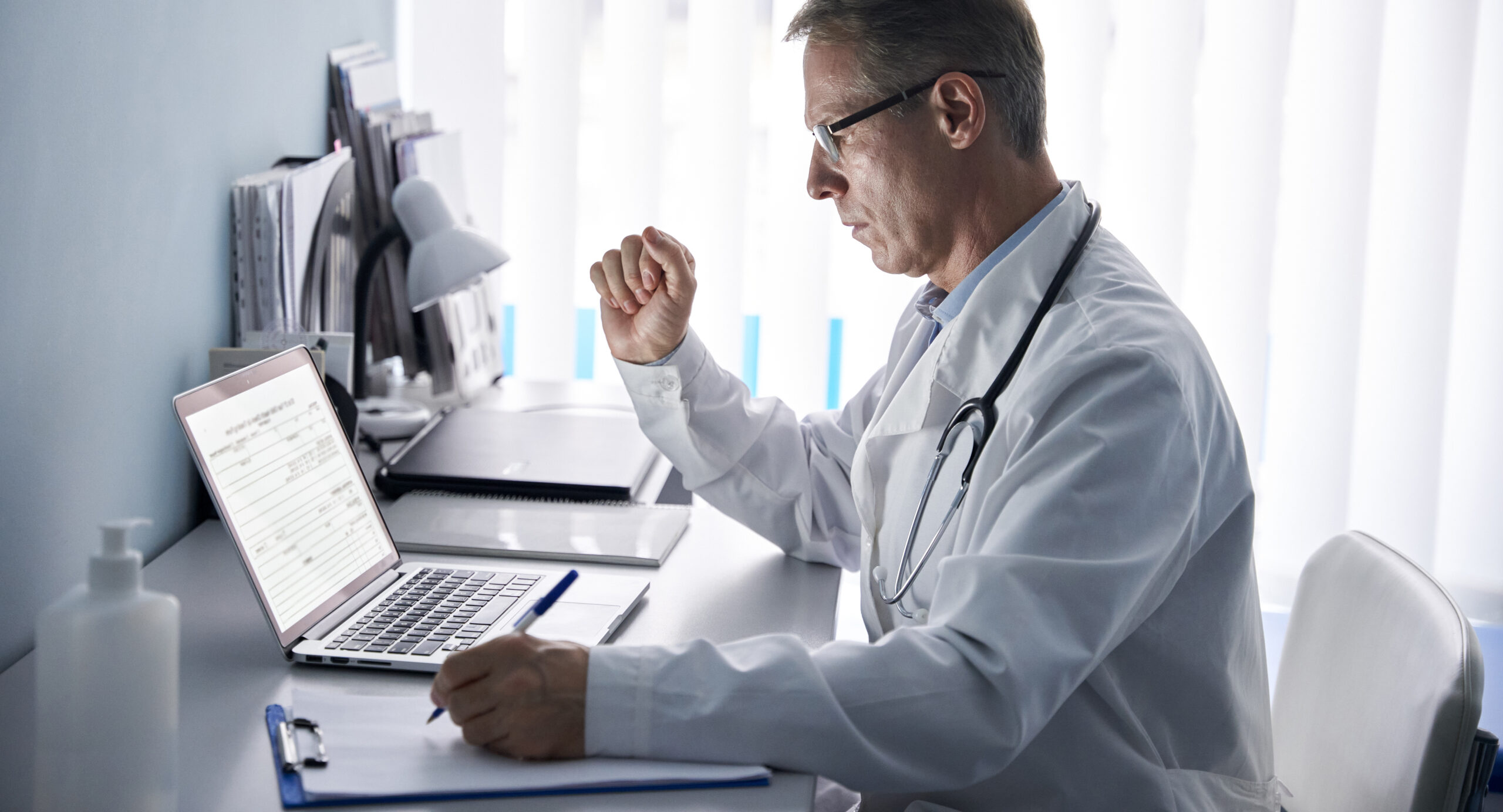 Serious,Mature,Old,Doctor,Physician,Using,Laptop,Tech,In,Hospital