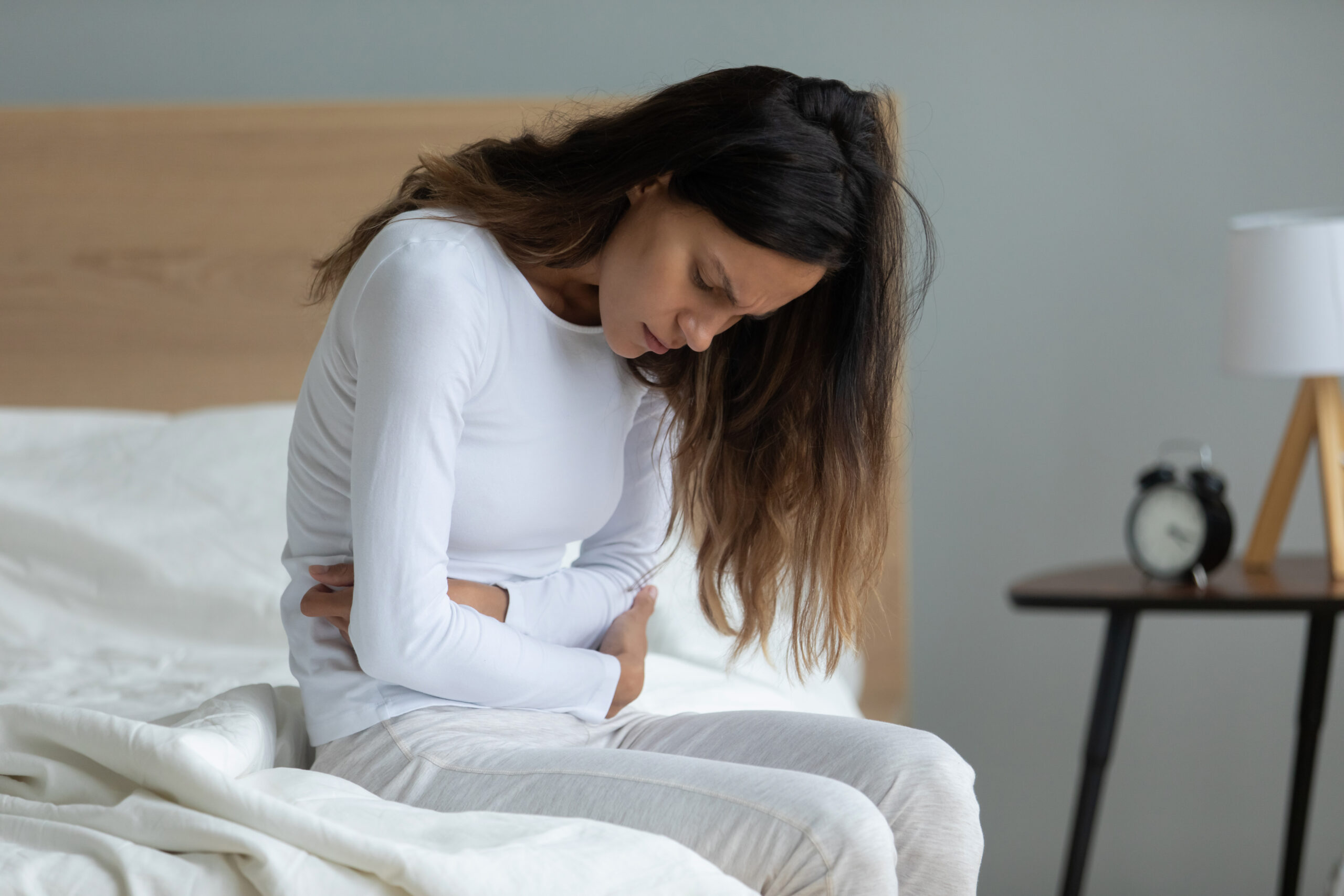 Unhealthy,Woman,Sit,On,Bed,Touch,Stomach,Suffer,From,Severe